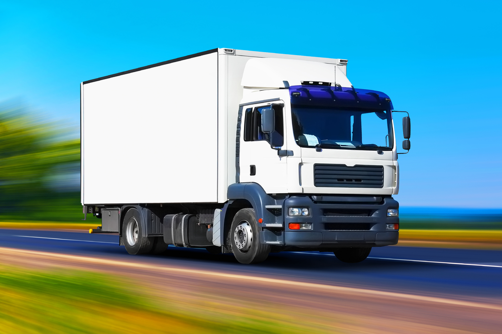 创意抽象航运业物流运输和货物货运工业商业概念白色送货卡车或集装箱汽车拖车在道路道路或高速公路上具有高速运动模糊效果